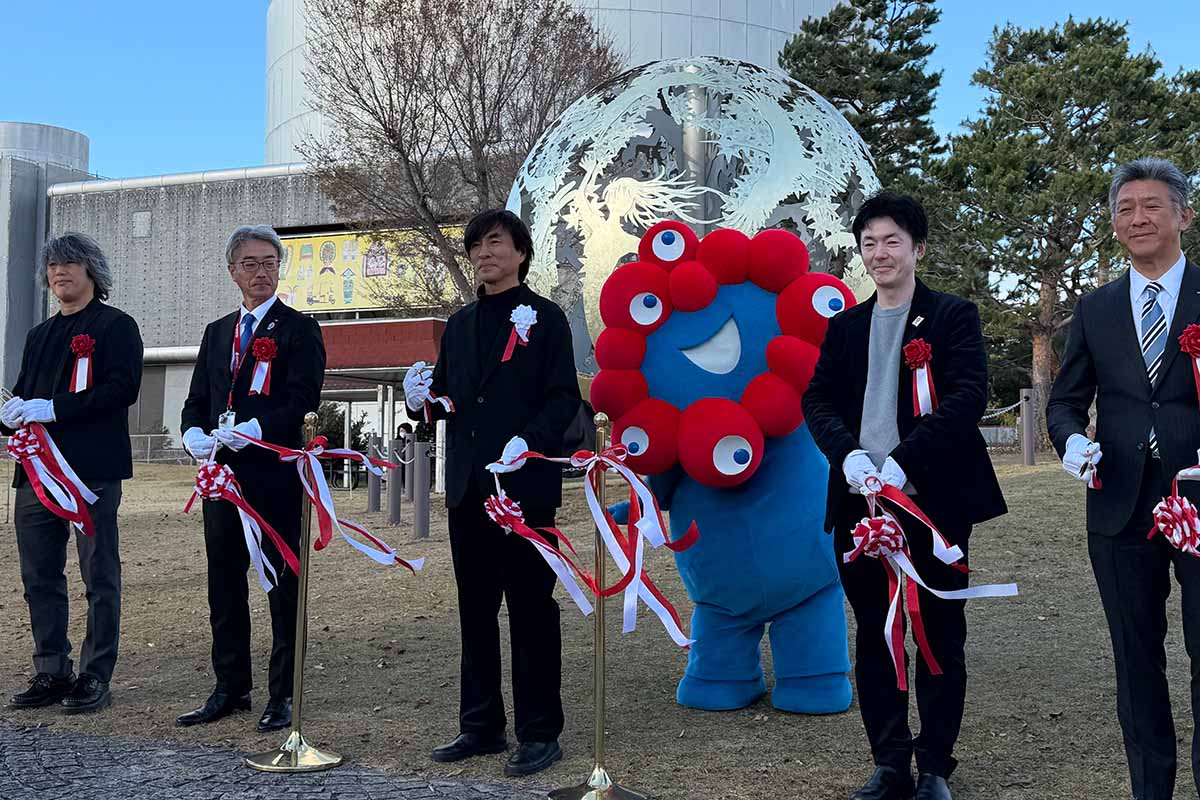 モニュメント「いのち球」移設セレモニーに参加した河森正治プロデューサー（左から3人目）やミャクミャクら関係者（撮影：2025年12月5日）