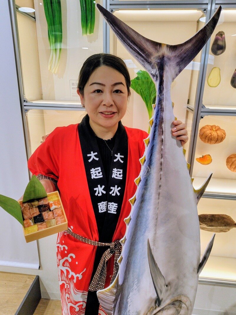 自分が作った箱寿司と大きなマグロを持って記念撮影をする参加者（９月26日撮影、大阪・関西万博）