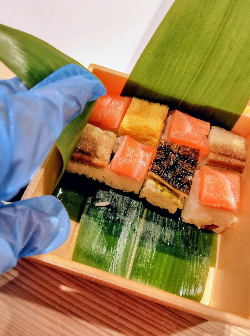 アート作品を作る気持ちで色とりどりの押し寿司を箱に詰める筆者（９月26日撮影、大阪・関西万博）