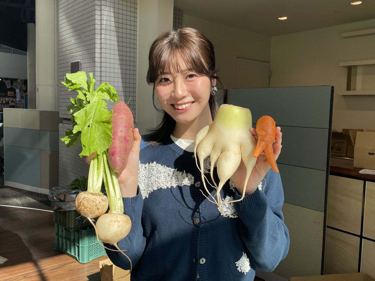 カンテレSDGsフェスタwithミライーね！（2025年11月8日） 規格外野菜を手に取る田中友梨奈アナ