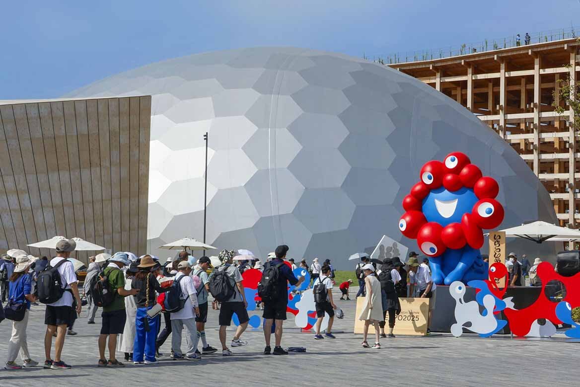 「ミャクミャク」のモニュメント像前で写真撮影のために並ぶ来場者（2025年8月28日）