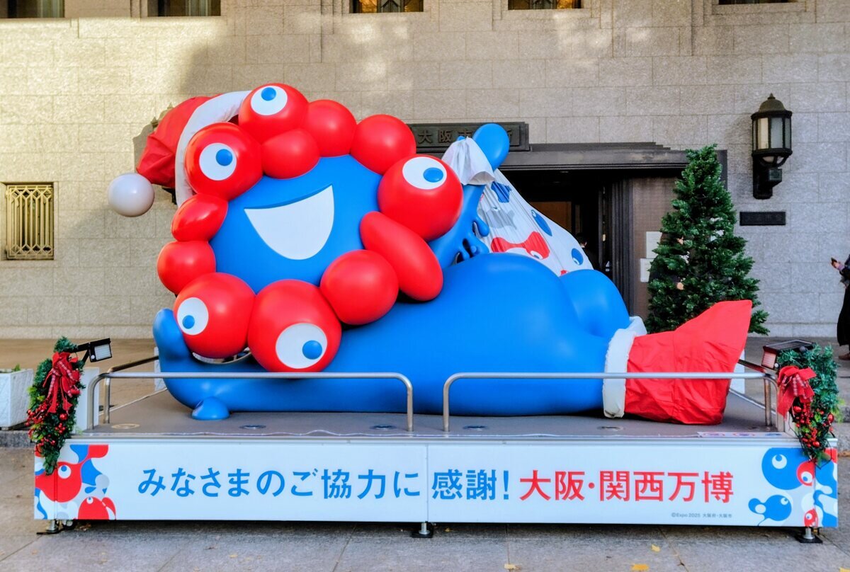 大阪市役所前に戻ってきたサンタ衣装を着た寝そべりミャクミャク（12月12日撮影、大阪市北区）