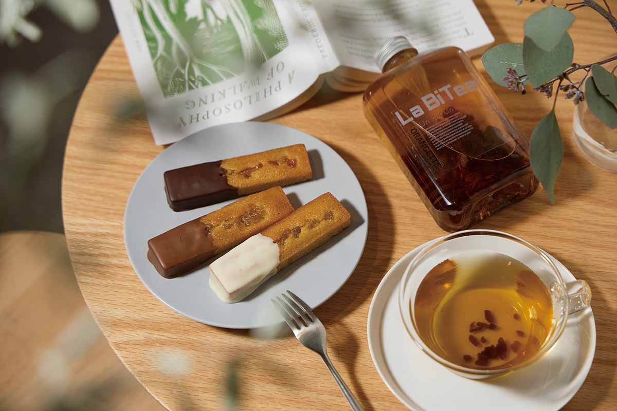 オレンジオイルで香りづけしたカカオハスクのハーブティー「ラビティー・オランジェット」（写真右・3g入り756円）に、オランジェット風の「リブレス」の「フィナンシェオランジェット」（各1個入り、各378円）のマリアージュ