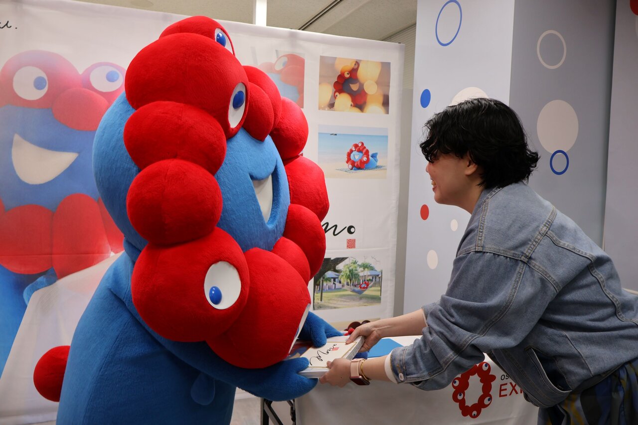 ミャクミャクから写真集とサイン入り色紙カードを手渡され、喜ぶファン（４月13日、大阪市北区）