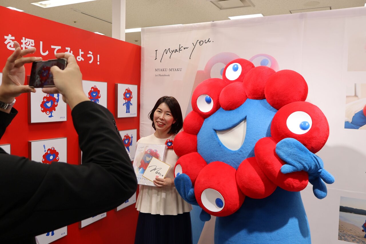 ミャクミャクと記念撮影をするファン（４月13日、大阪市北区）