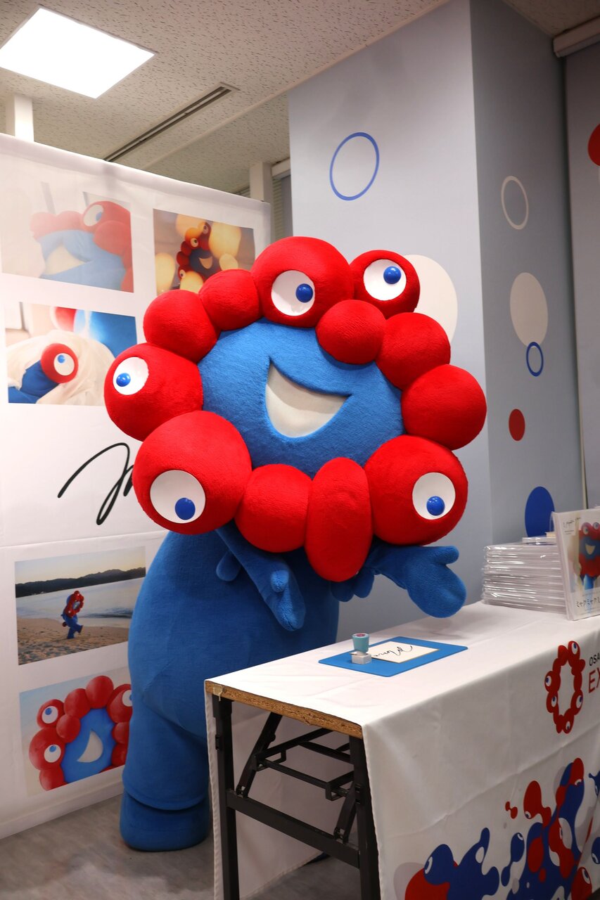 ファンが来るのをソワソワしながら待つミャクミャク（４月13日、大阪市北区）