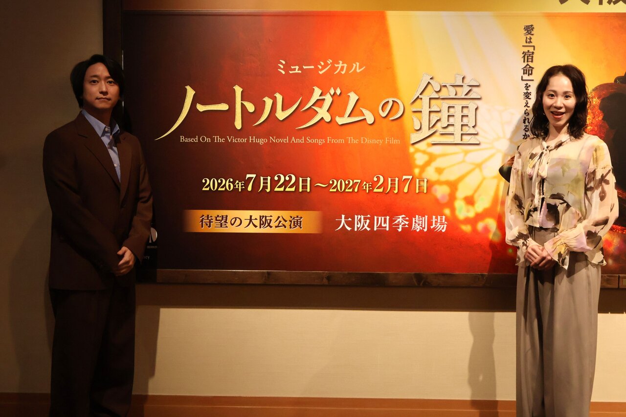 『ノートルダムの鐘』の巨大ポスターの前に立つ寺元健一郎さん（左）と宮田愛さん（４月13日撮影、大阪四季劇場）