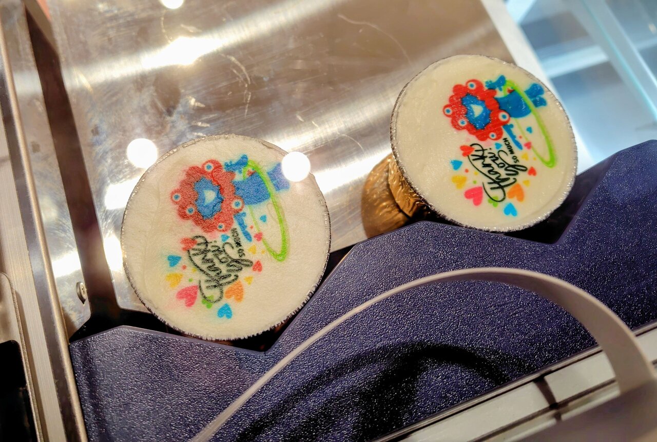 店内でイラストをプリントする様子が見られる「ミャクミャクチーズケーキ」（４月27日、大阪市北区）