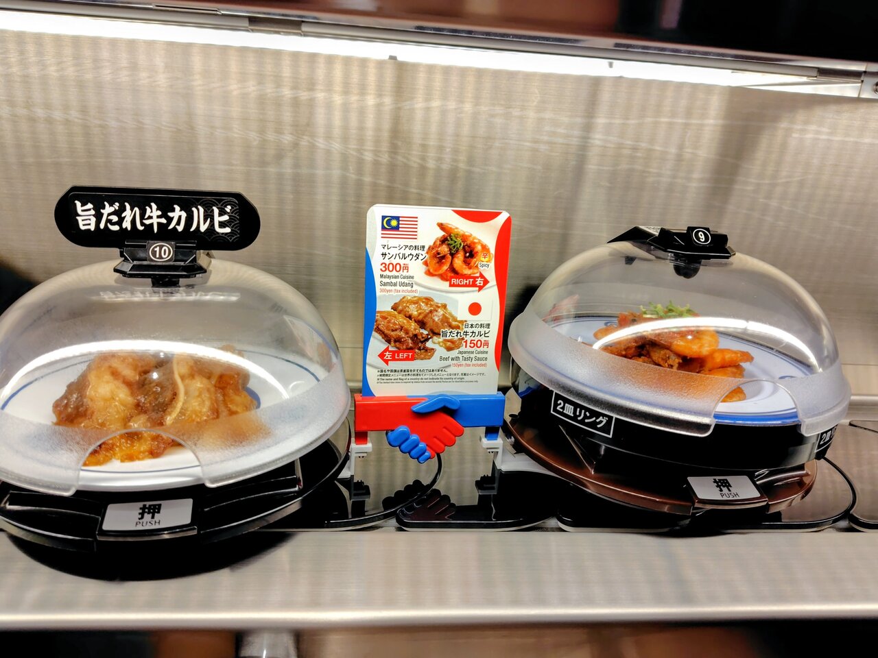 万博のイメージカラーである赤と青の“手”で、寿司と世界の料理をつなぐ「抗菌寿司カバー鮮度くん」（５月13日、大阪市中央区）