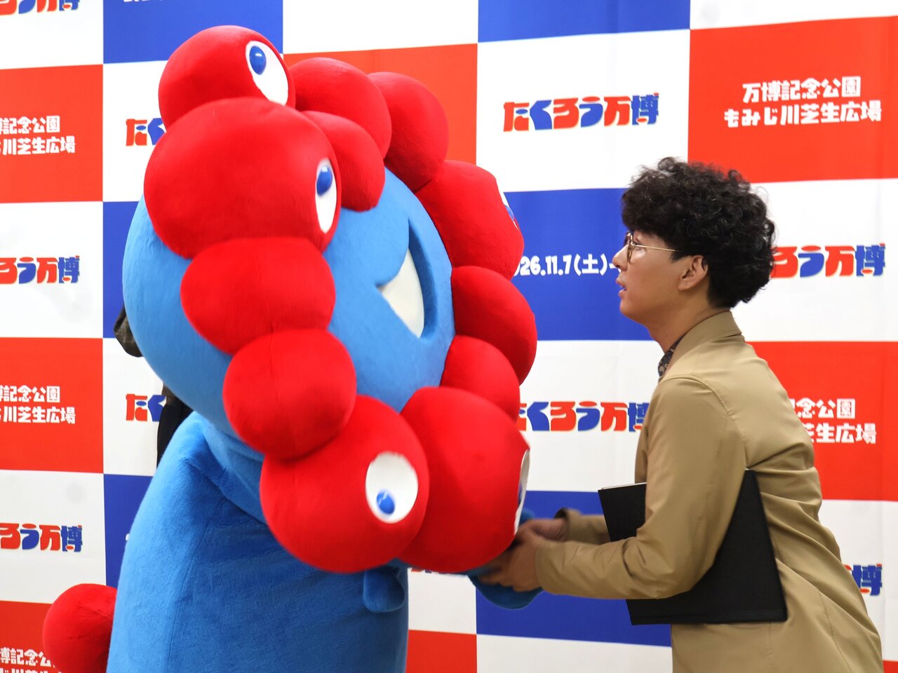 ミャクミャクと握手する木村バンドさん（７月３日、大阪市中央区）