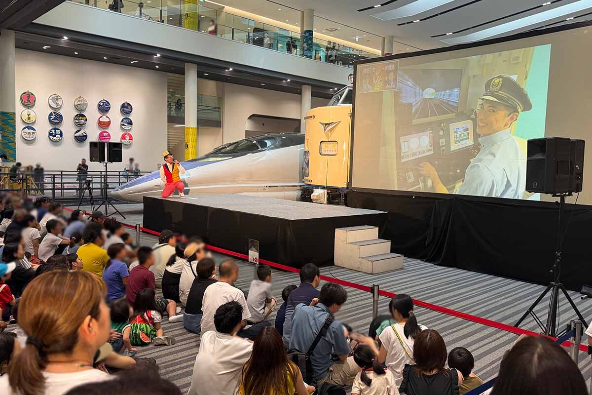 別会場から中継で運転シミュレーター対決を届ける小島よしお（2026年7月・京都鉄道博物館）