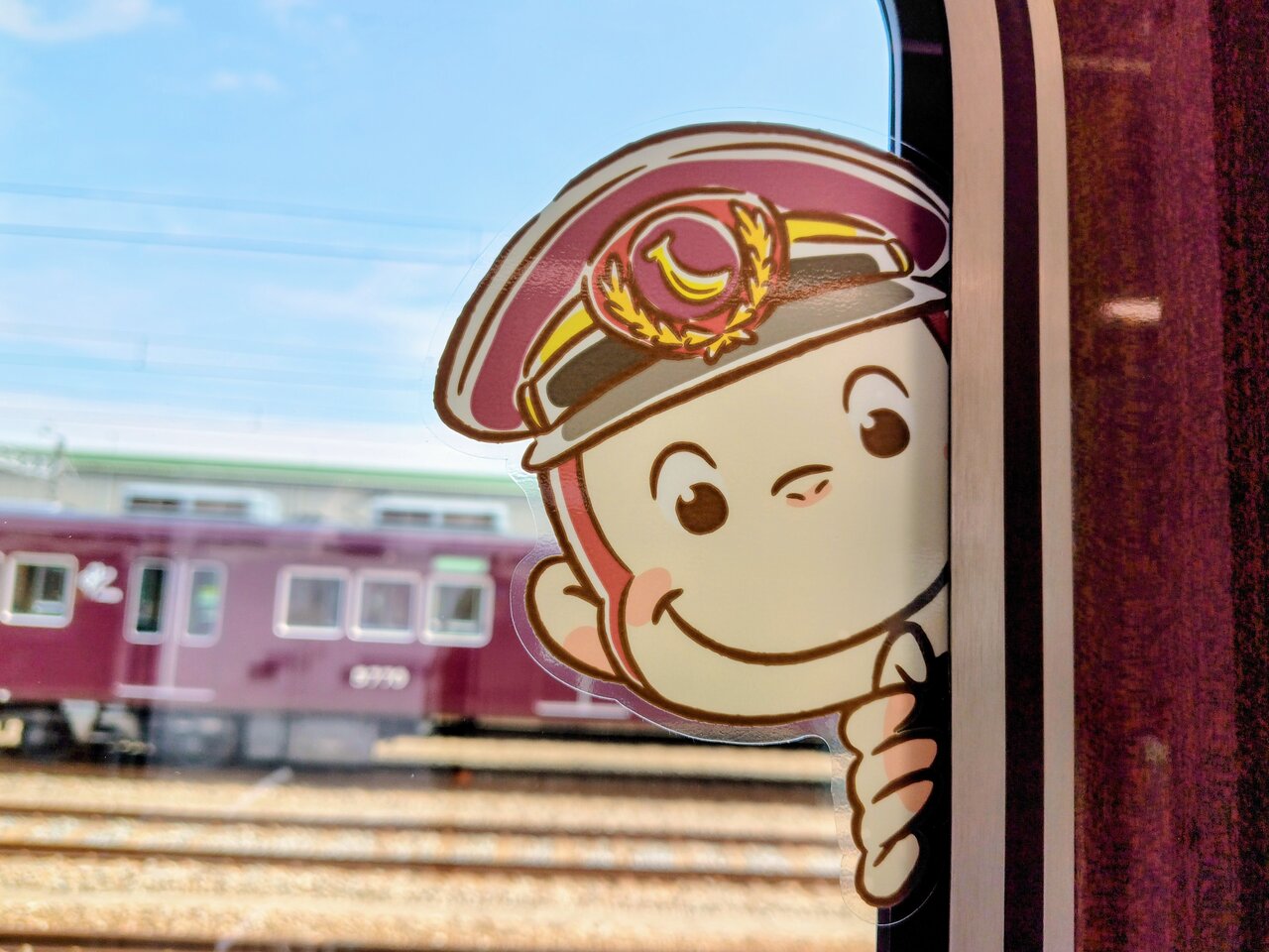 ドアガラスから顔をのぞかせる「おさるのジョージ」（７月30日、兵庫県宝塚市）　©&®UCS LLC and HC LLC ©Hankyu Corp.