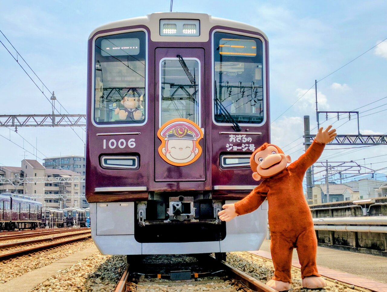 「おさるのジョージ号」の正面でポーズを決める「おさるのジョージ」（７月30日、兵庫県宝塚市）　©&®UCS LLC and HC LLC ©Hankyu Corp.