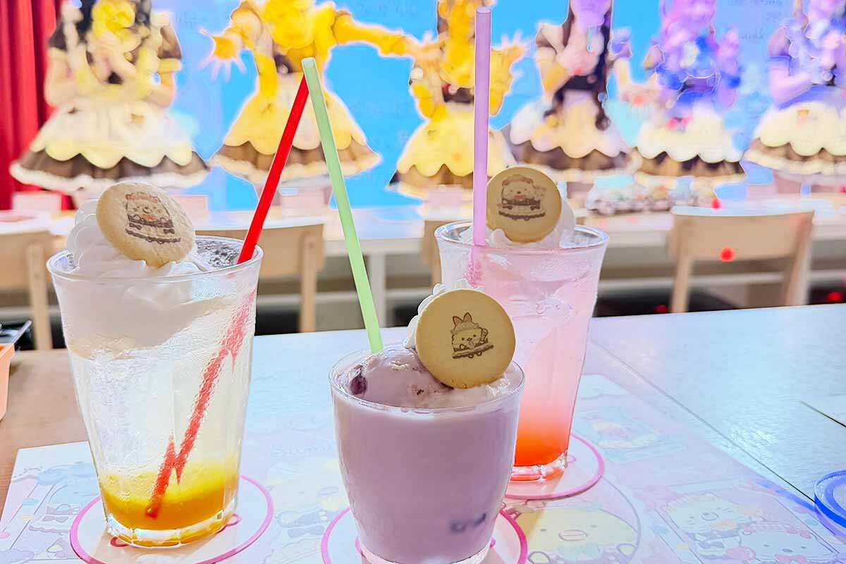 ドリンクにはそれぞれのキャラクターのクッキも。左から「マンゴー+ソーダ」（ねこ）、「むらさきいも+ミルク」（えびてんのしっぽ）、「ピンクグレープフルーツ+ソーダ」（しろくま）（2026年8月・あっとほぉーむカフェ大阪本店）