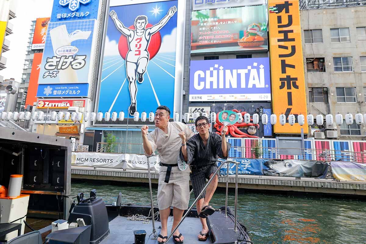 グリコサインの前でポーズを取るアンタッチャブルの柴田英嗣（右）と山崎弘也（2026年8月・大阪市中央区）