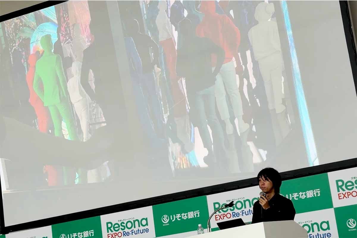 プロトタイプの「ヌルヌルネクサス」に3Dプリンタで作った人形を置いて検証する様子を説明する落合陽一氏（2026年8月・ATCホール）